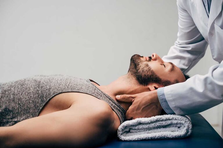 A chiropractor gently checks a patient's upper spine in a bright, clean clinical setting.