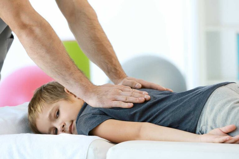 Pregnant woman receiving a gentle side-lying back treatment with supportive cushions.